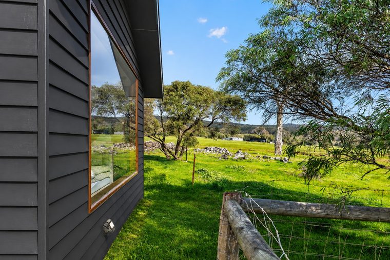 Paddock and fence line seen past the studio's dark cladding