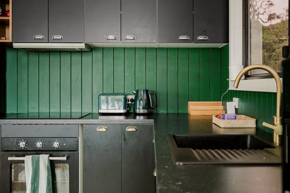 Oven, cooktop and bench with green splashback
